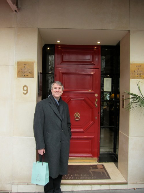 Mark standing by happy red door of nice hotel